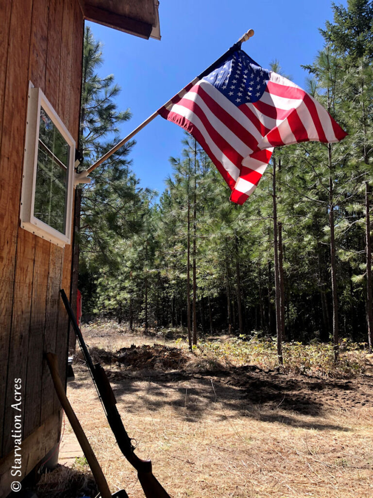 Flag flying over shotgun at cabin.