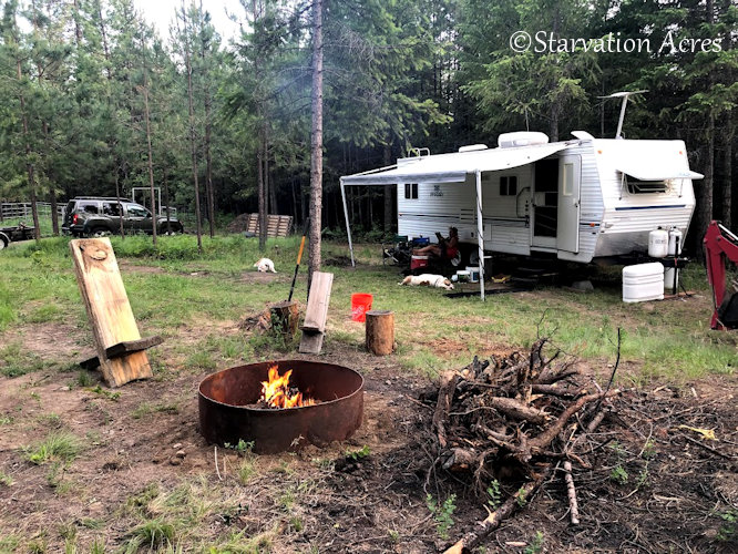 Campfire with trailer in background.